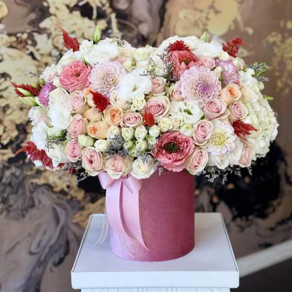 Pink and white floral arrangement in a round hat box with a ribbon