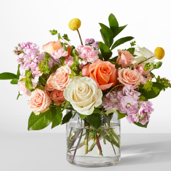 Bouquet of peach, white, and pink roses in a clear glass vase