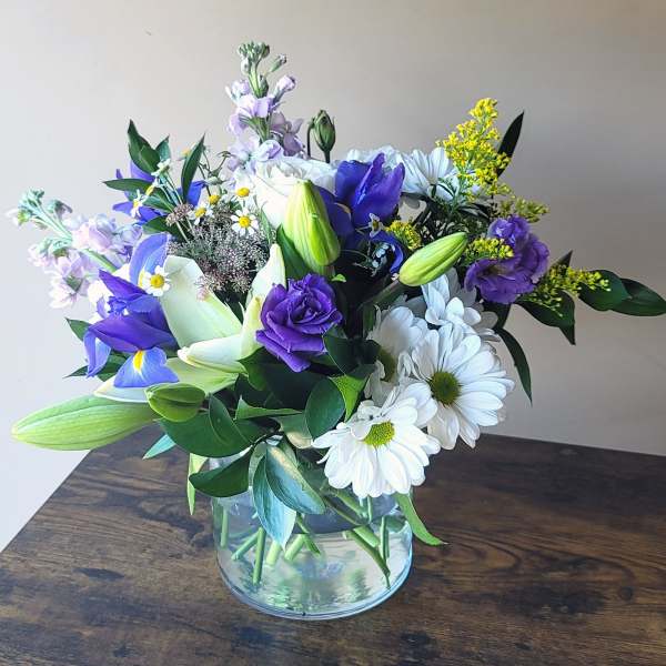 Purple and white mixed bouquet in a clear glass vase