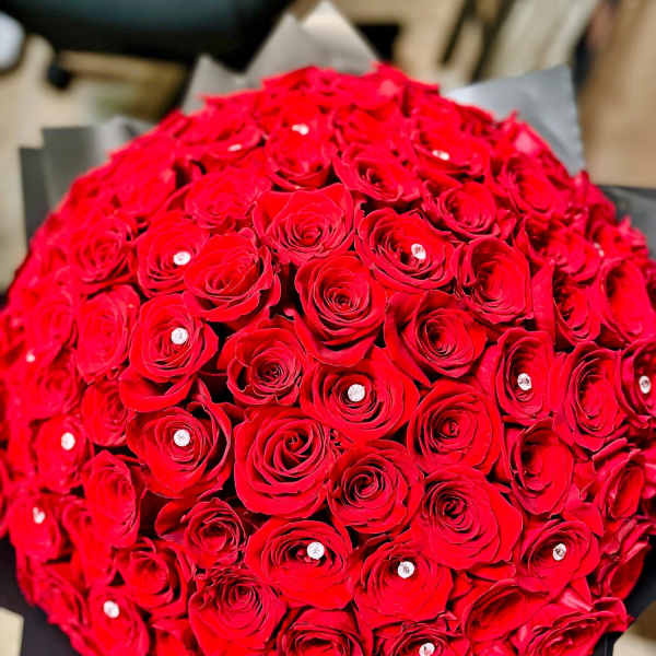 Round bouquet of red roses wrapped in black paper