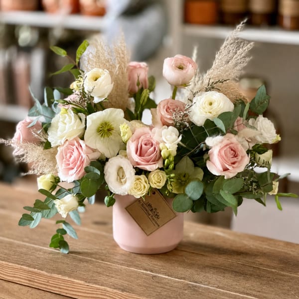 Pink and white roses in a blush vase with airy dried grasses