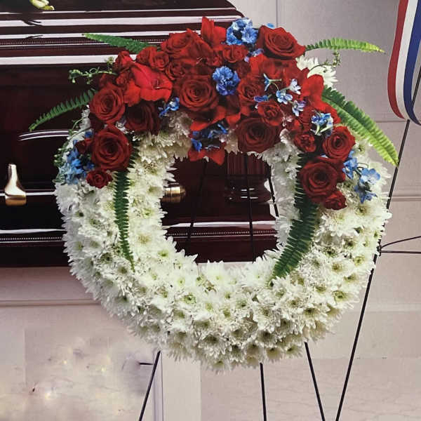 Circular funeral wreath of red roses and white flowers on a stand
