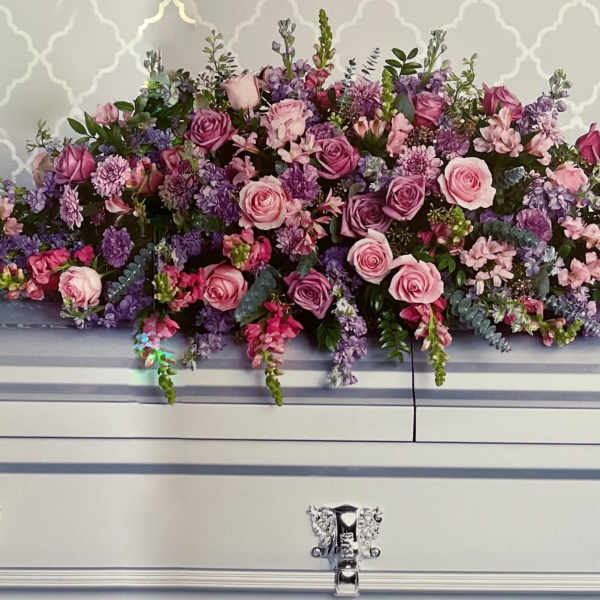 Large pink and purple floral spray on a white casket