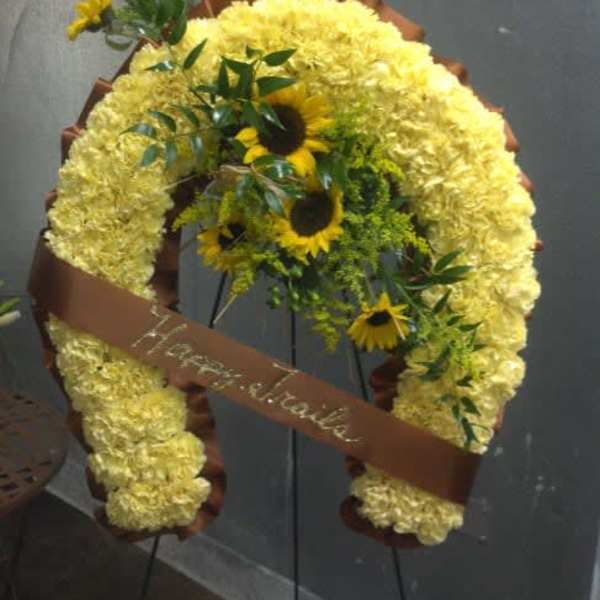 Yellow floral funeral wreath with sunflowers and a brown ribbon on an easel