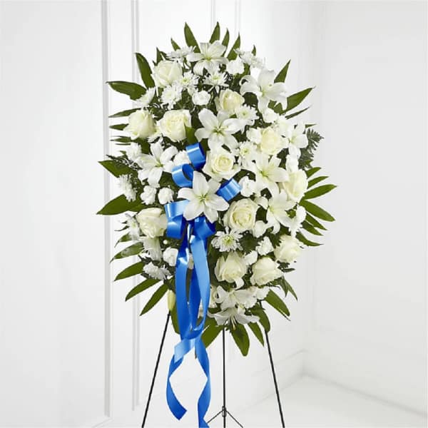 White floral standing spray with a blue ribbon on a black easel