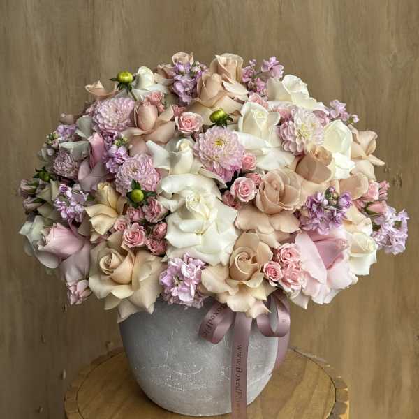 Large pastel bouquet of roses, chrysanthemums, and small pink flowers in a gray vase