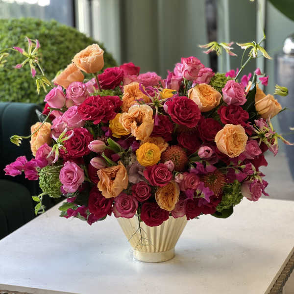 Mixed bouquet of pink, red, and peach roses in a gold vase