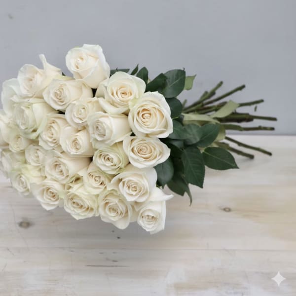Hand-tied bouquet of long-stemmed ivory roses resting on a light wooden surface