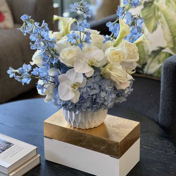Blue and white floral arrangement in a white vase on a table