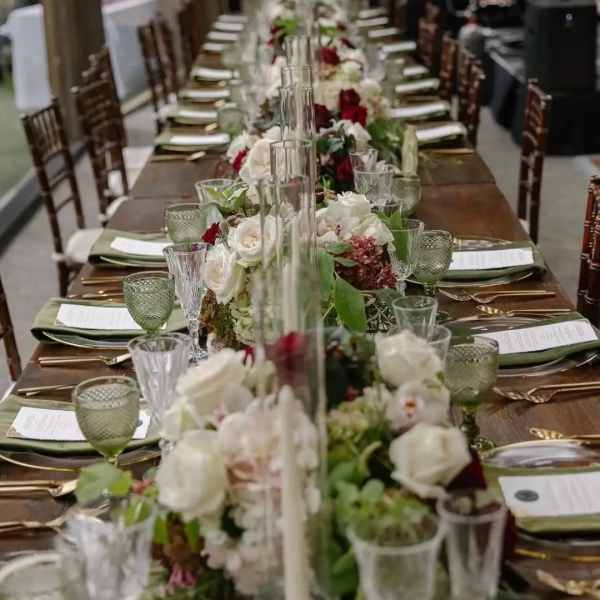 Long banquet table with white and red floral centerpieces in glass vases