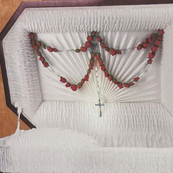 White casket with red rose garland and a small cross