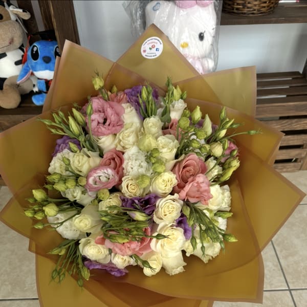 Mixed bouquet of pink, white, and purple flowers wrapped in brown paper