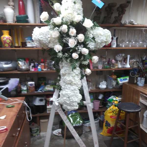 White floral standing cross on a white easel