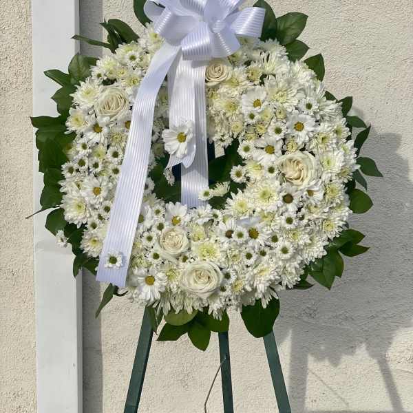 White floral wreath with a ribbon bow on an easel
