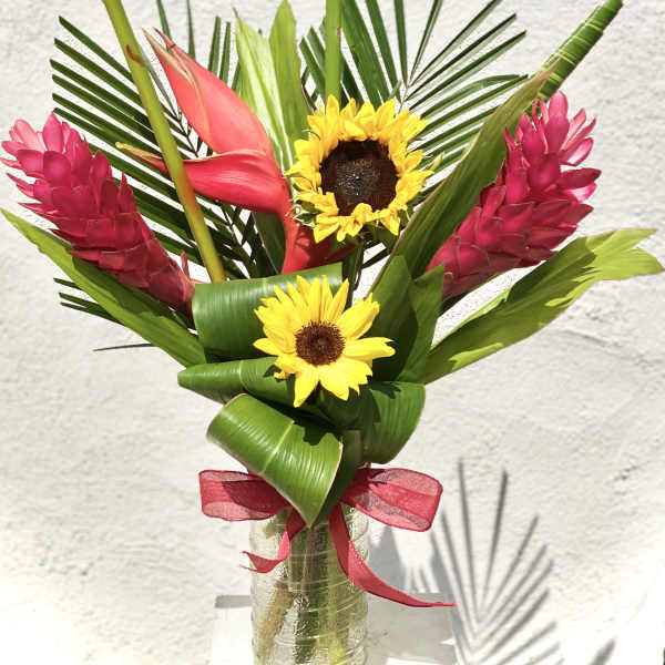 Tropical bouquet with sunflowers and pink ginger in a glass vase