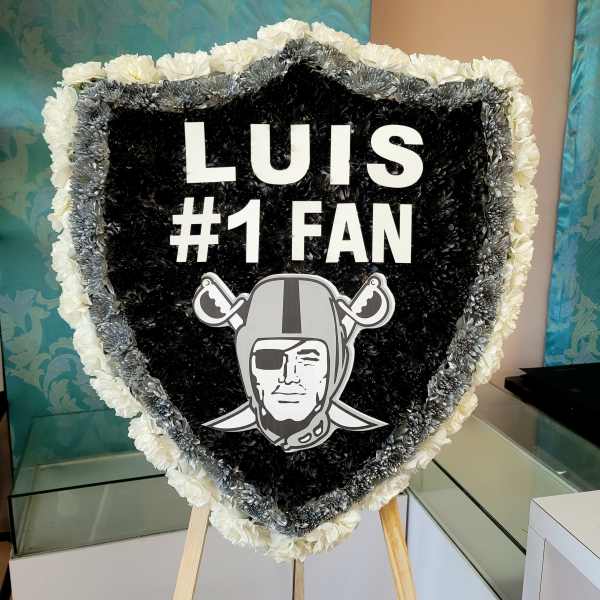 Heart-shaped floral tribute with black, white, and silver flowers and a sports logo