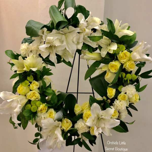 White and yellow floral wreath on a black stand