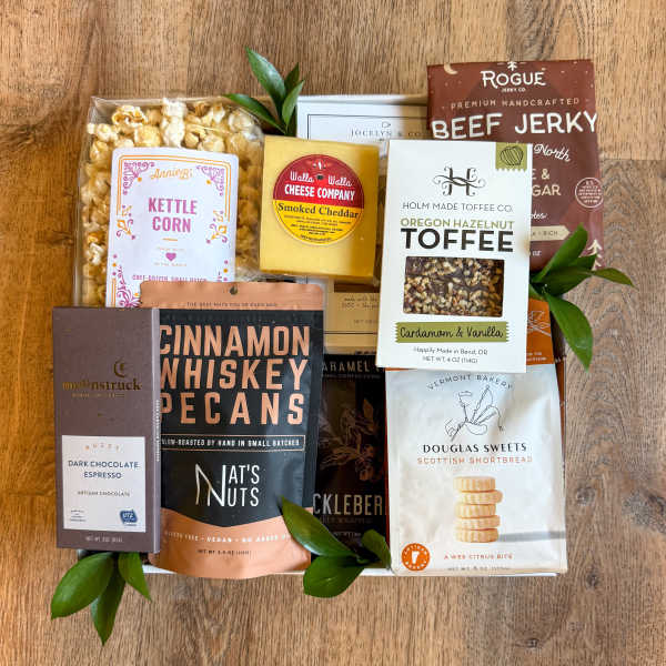 Assorted gourmet snack gift set with packaged treats on a wooden surface