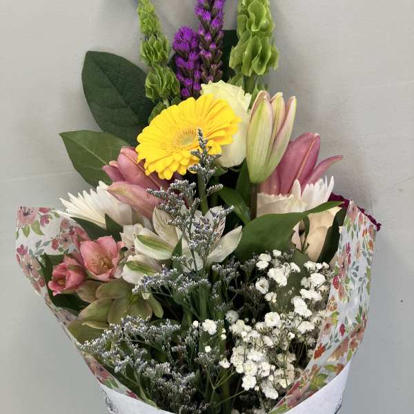 Mixed bouquet with pink lilies, yellow gerbera, and white filler flowers