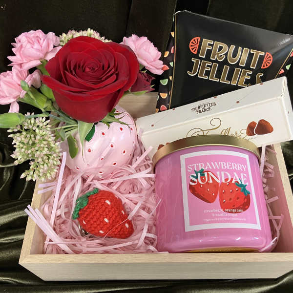 Gift box with a red rose, pink flowers, candy, and a pink candle