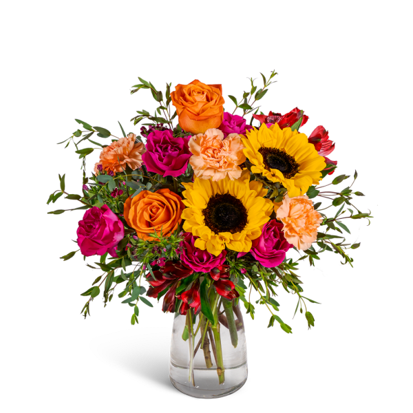Bouquet of orange and pink flowers with sunflowers in a clear glass vase