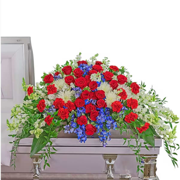 Red roses, blue flowers, and white blooms arranged on a casket