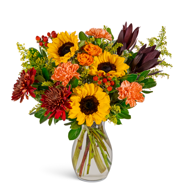 Bouquet of sunflowers, orange roses, and carnations in a clear glass vase