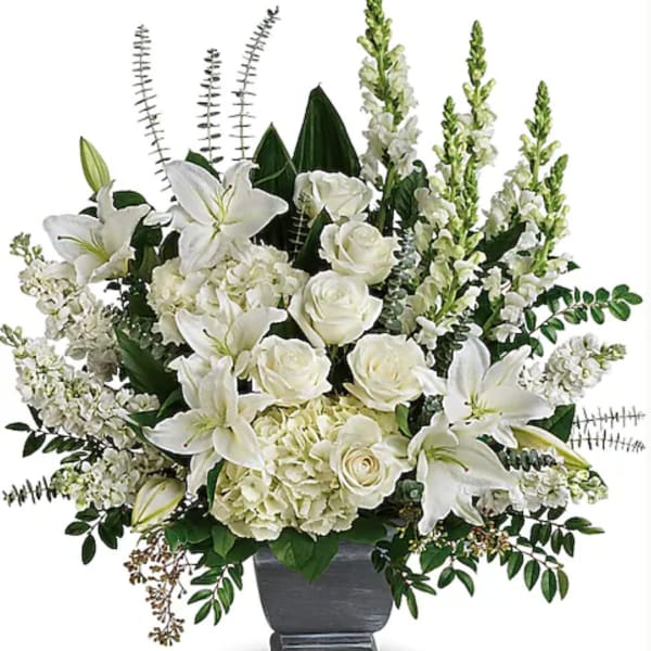 White lilies and roses arranged in a gray urn vase