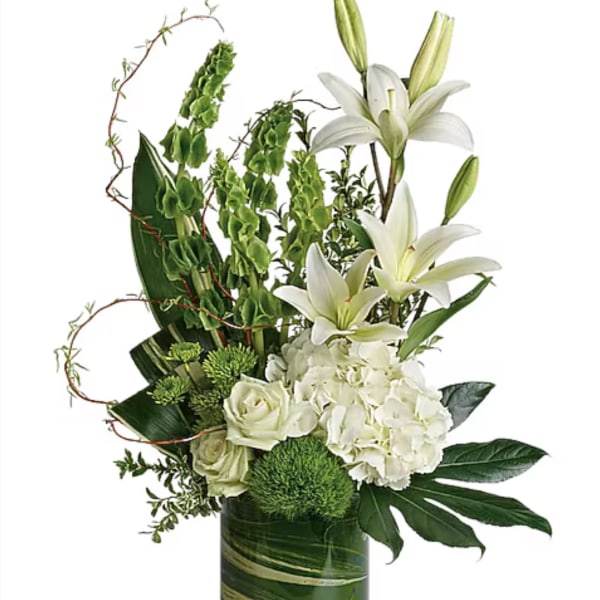 White lilies and roses arranged in a tall green glass vase