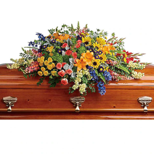 Colorful floral casket spray with mixed blooms on a wooden coffin