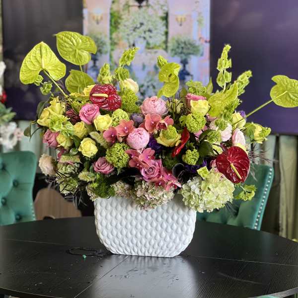 Mixed pink and green floral arrangement in a white textured vase