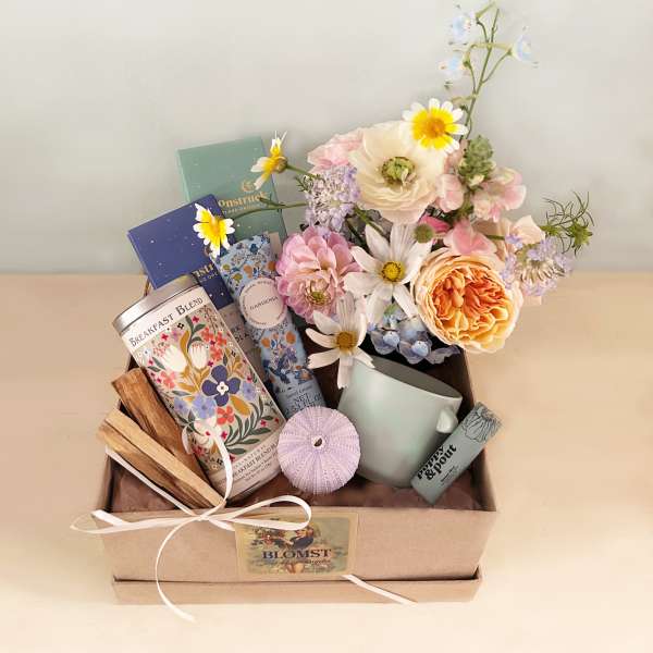 Gift box with pastel flowers, tea tins, and a mug