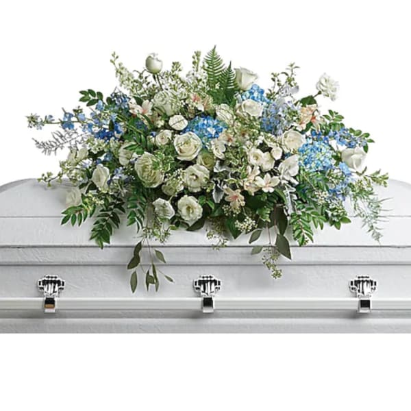 White and blue floral casket spray with greenery