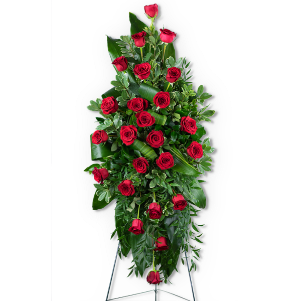 Tall standing spray of red roses with lush greenery on a black easel