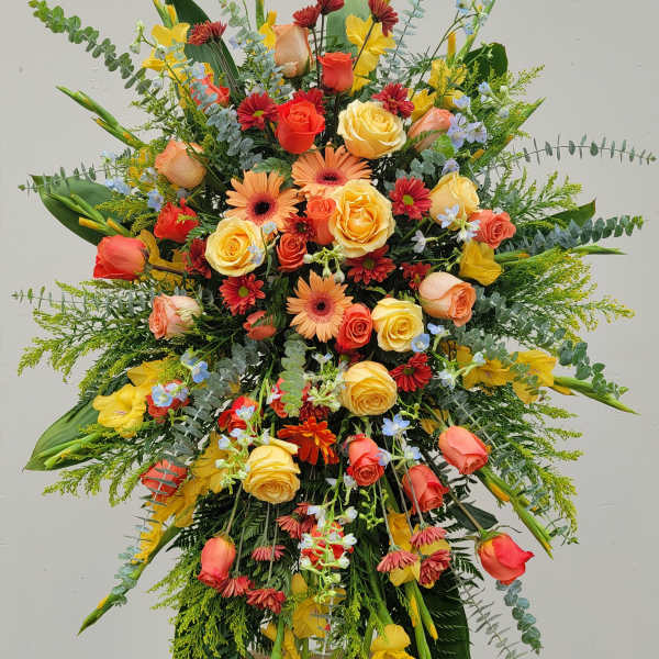 Large standing floral spray with roses, gerbera daisies, and yellow blooms