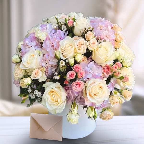 Bouquet of pastel roses and hydrangeas in a white hatbox with an envelope