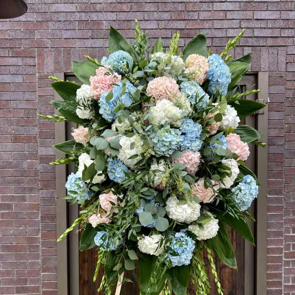 Large standing spray of blue, white, and pink hydrangeas