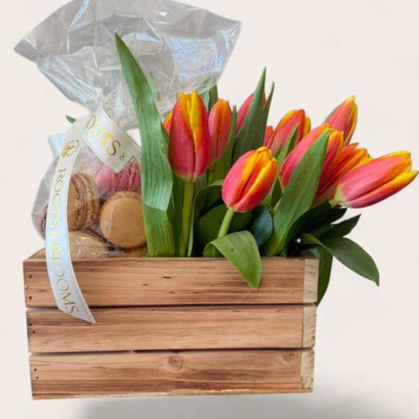 Tulip bouquet in a wooden crate with a clear gift bag and macarons