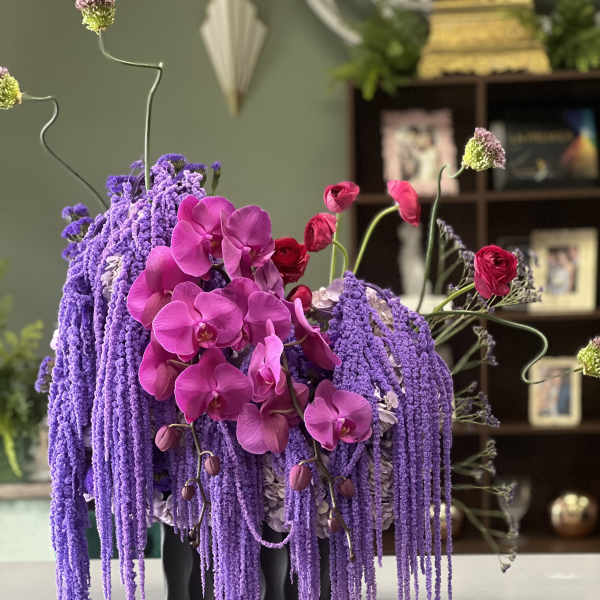 Purple and pink orchid arrangement in a black vase