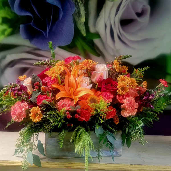 Colorful floral arrangement with lilies, roses, and mums in a wooden box