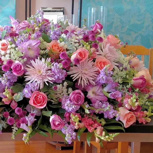 Large pastel floral arrangement with pink and lavender blooms on a table