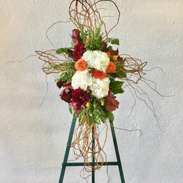Tall floral arrangement with white and orange blooms on a green stand