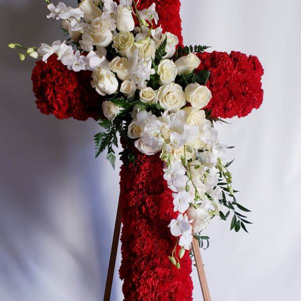 White roses and orchids arranged on a red floral cross