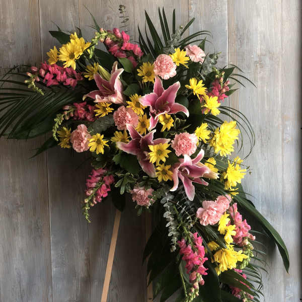 Standing floral spray with pink lilies, yellow daisies, and carnations