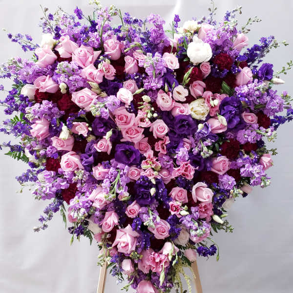 Heart-shaped bouquet of pink and purple flowers on a stand