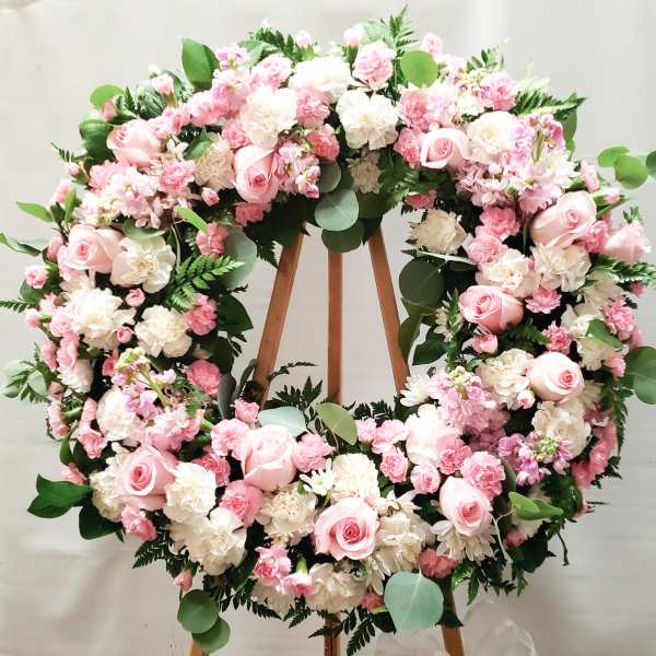 Large pink and white floral wreath on a wooden stand