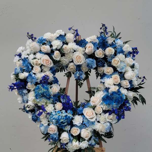 Heart-shaped floral wreath of white and blue roses on an easel