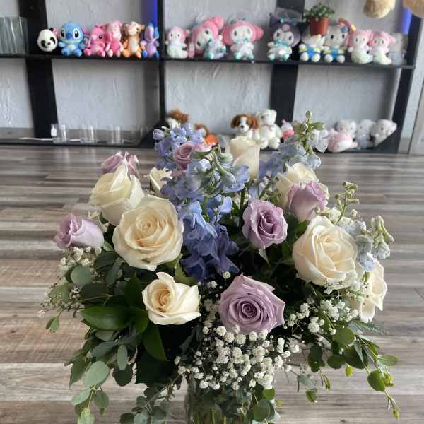 Pastel roses and blue delphinium in a clear glass vase