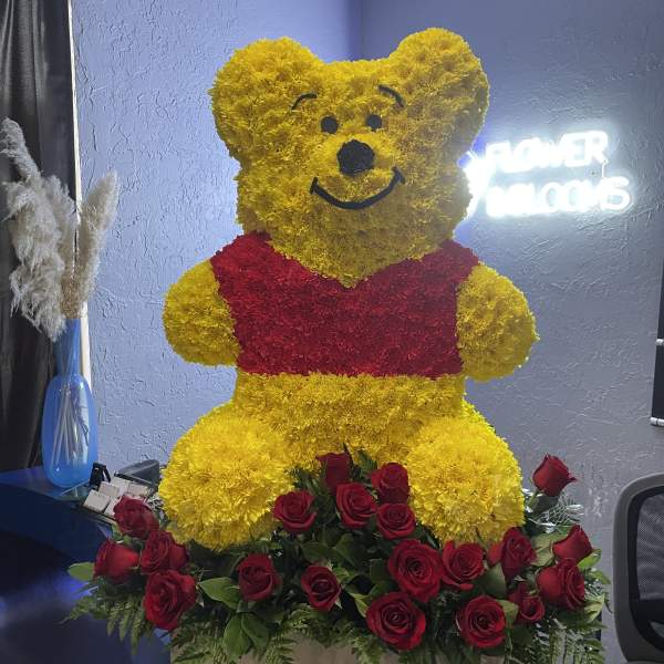 Winnie the Pooh floral sculpture with red roses at the base
