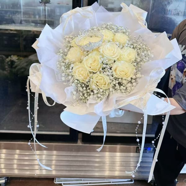 Bouquet of pale yellow roses wrapped in white paper with ribbon accents